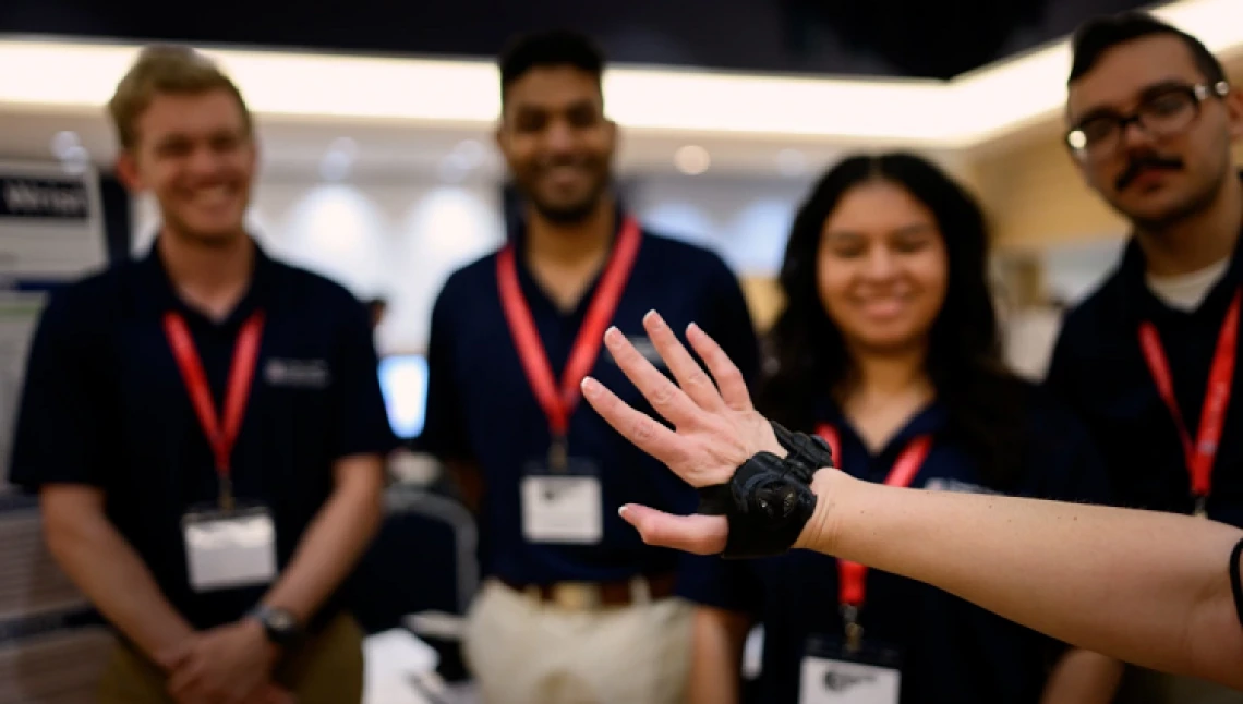 A team of engineering students around a wrist brace at Design Day