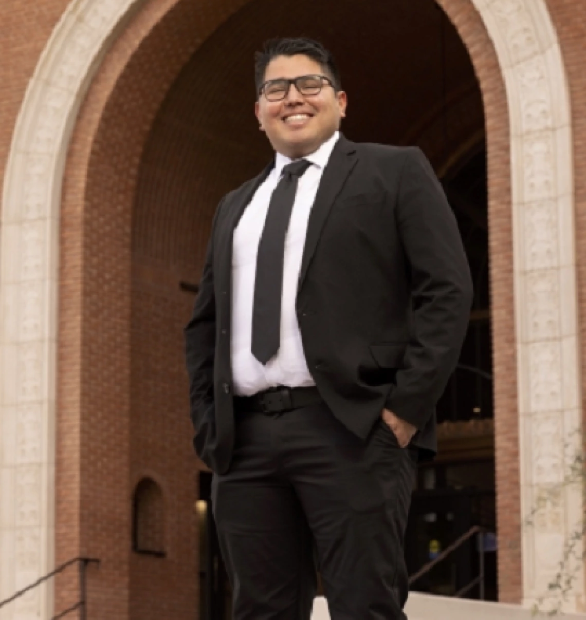 person in suit, wearing glasses, smiling