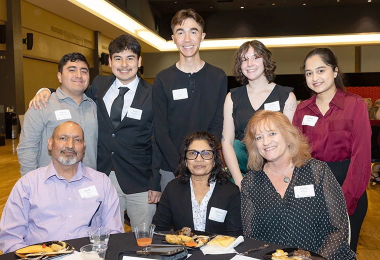 people seated or standing at table, smiling