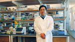 BME assistant professor Minkyu Kim wearing a lab coat and surrounded by various scientific equipment. 