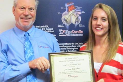 A man in a blue shirt hands a framed certificate to a woman wearing a red-and-white striped shirt.