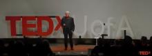 Screen capture of video of David Galbraith on stage at TEDxUofA, with the letters appearing behind him