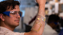 A biomedial engineering graduate student in the Philip Gutruf Lab inspects a wearable sensor.