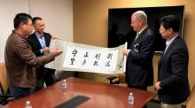 Professors from Beijing Normal University present a banner to the University of Arizona interim dean of the College of Medicine and the UA librarian