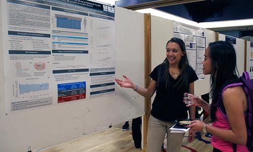 Michelle Gary explains her research to a fellow student at BME Design Day on March 2