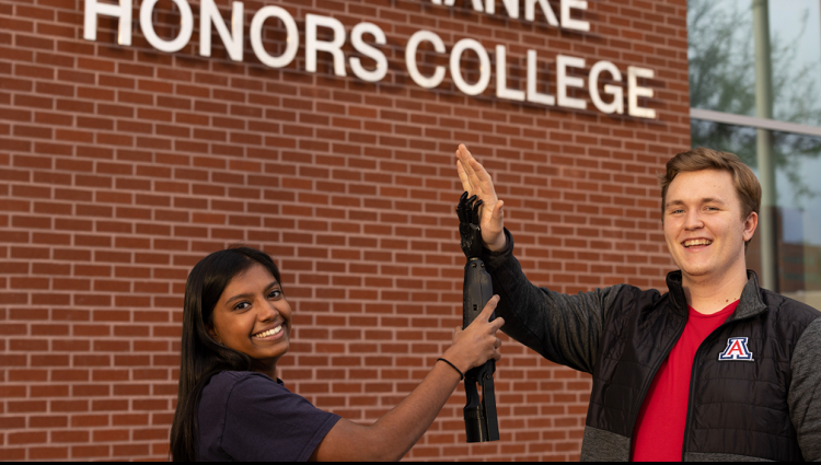 Collin Preszler and Nisha Rajakrishna do a mock high-five with a prosthetic arm