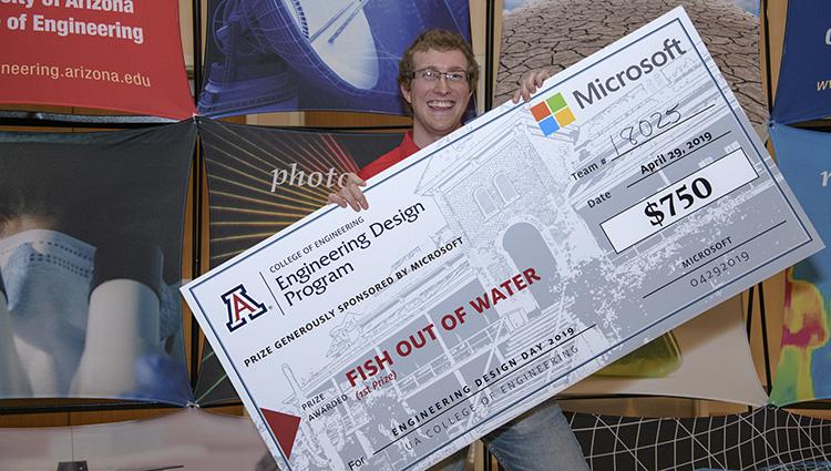 A smiling man holds a comically large check tilted across his chest