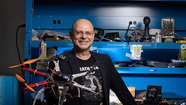 Wolfgang Fink in his lab next to a drone with propellers 