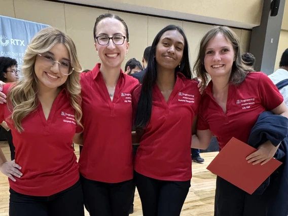 Four women pose for a photo in red t-shirts.