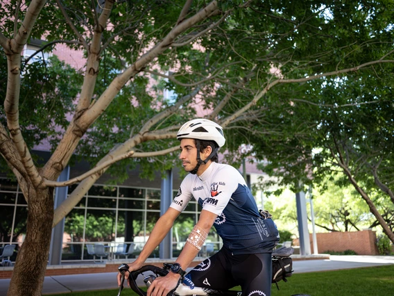 A participant using wearable health device rides a bicycle at the University of Arizona.