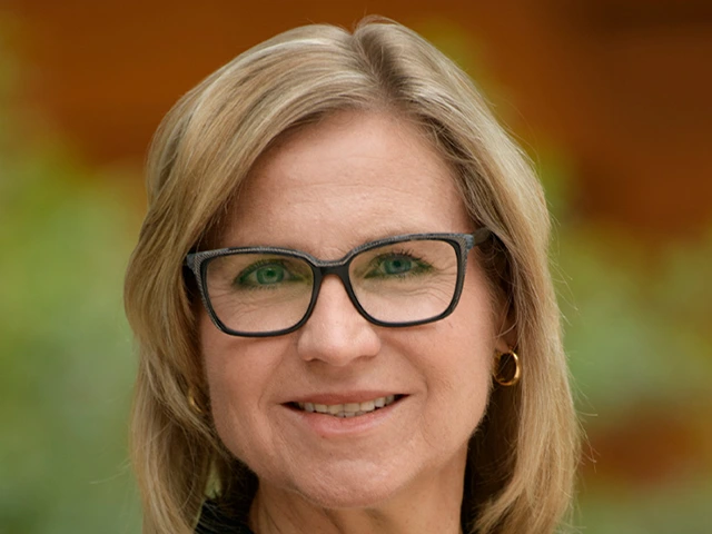 person with blonde hair and blue eyes, wearing glasses
