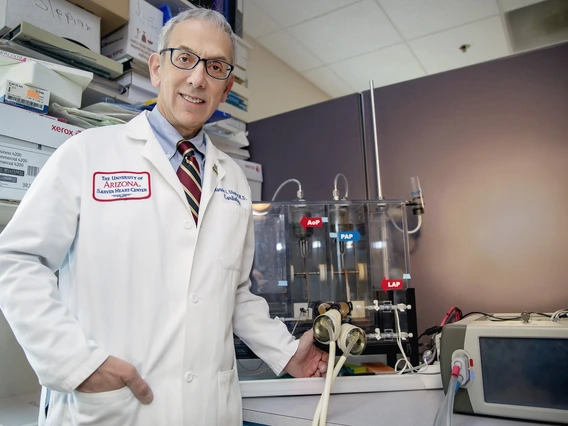 A man in a white lab coat stands in front of a medical device.