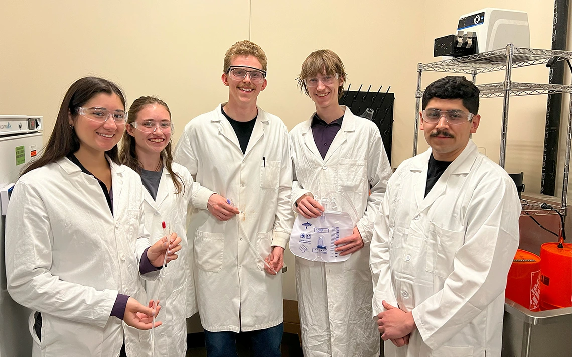 Five students pose for a photo in lab coats.