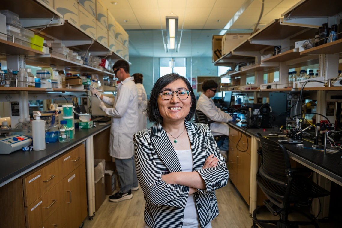A women in a gray suit takes a photo in a science lab