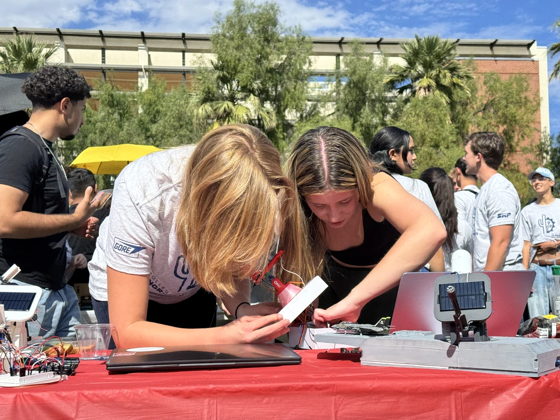 Two young women fix a solar tracker.