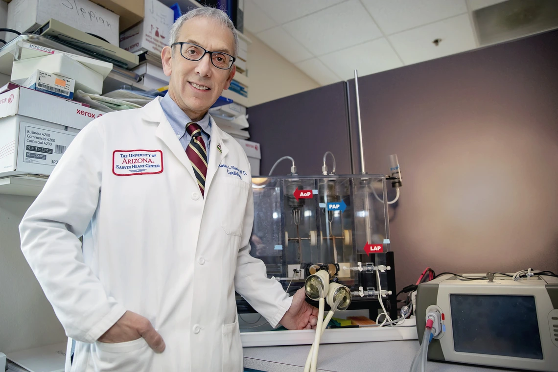 A man in a white lab coat stands in front of a medical device.