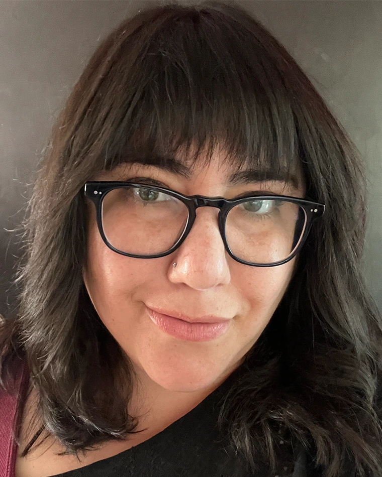 person with dark hair and glasses, smiling