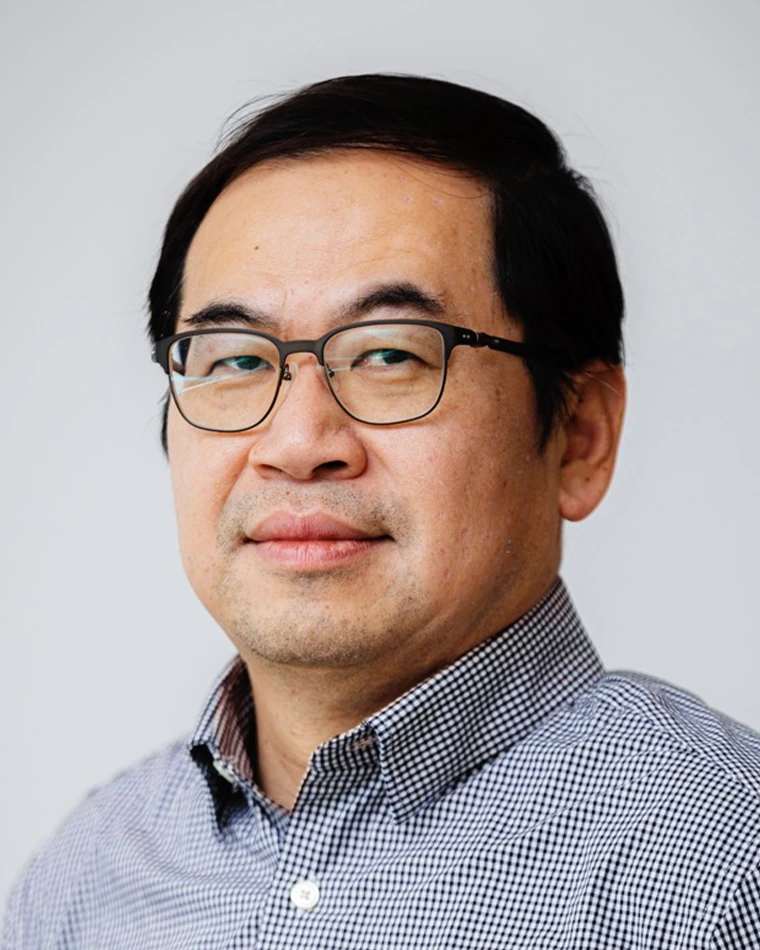 person with short black hair, wearing glasses and plaid shirt
