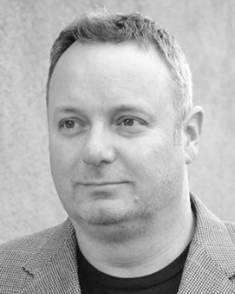 black and white photo of person with short hair, plaid jacket and dark t-shirt