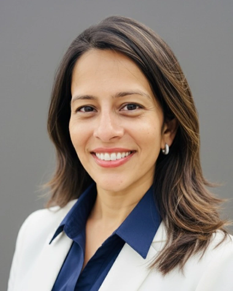 person with long, dark hair, wearing white blazer, blue blouse and earrings