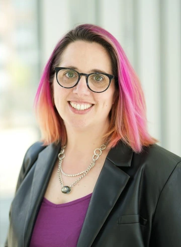 person wearing glasses, black suit and purple shirt