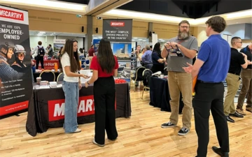 group of people, standing in front of an iExpo table with signage