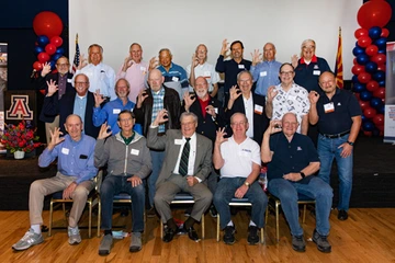 alumni, seated and standing, smiling