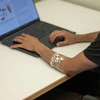 A man types on a computer while wearing a transparent arm cuff.