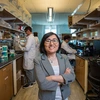 A women in a gray suit takes a photo in a science lab