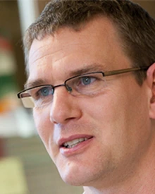 person with short, dark hair, wearing glasses
