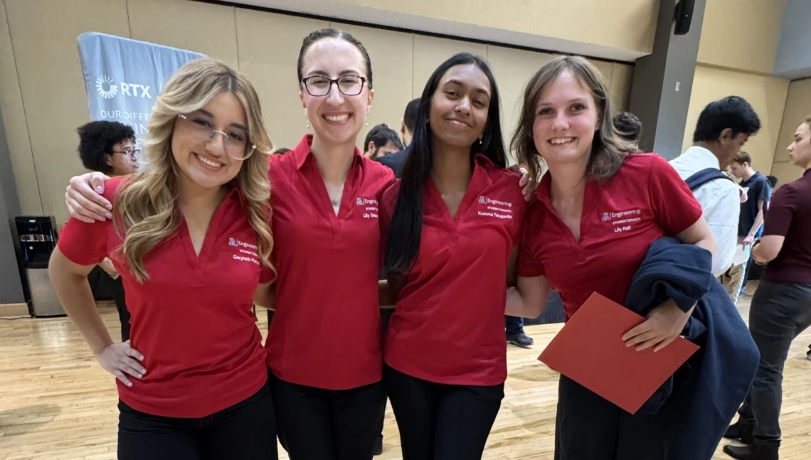 Four women pose for a photo in red t-shirts.